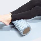 Person using a foam roller on a light gray surface
