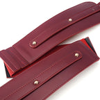 Close-up of a red leather belt with gold buckles on a white background