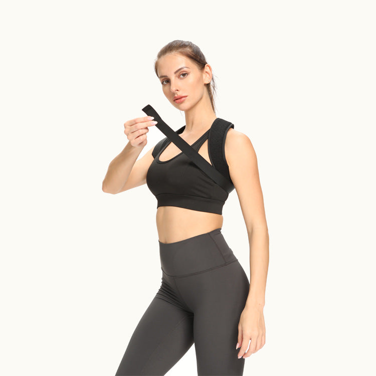Woman wearing a black sports bra and gray leggings holding a black strap.