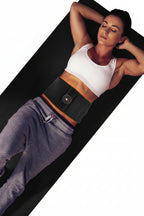 Woman lying on a black mat wearing a black waist trainer.