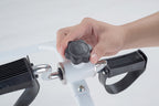Hand adjusting a black knob on a white and black device with a light gray background