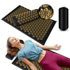 Acupressure mat with gold needles, a pillow, and a pump on a white background.