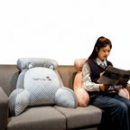 Woman sitting on a couch with a lumbar pillow, surrounded by decorative items.