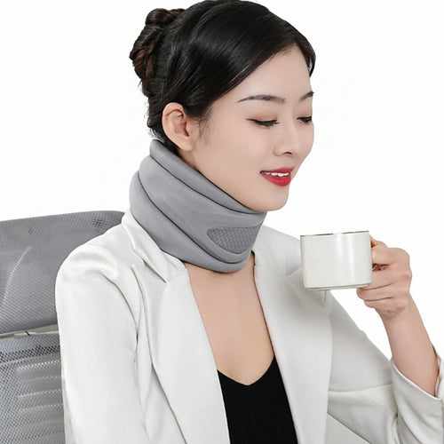 Woman wearing a gray neck pillow holding a mug indoors.
