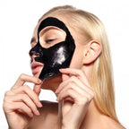 Woman applying a black face mask with a blurred background
