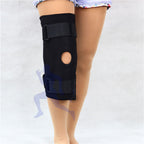 Black knee brace on a person's leg against a white background