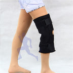 Black knee brace on a person's leg against a plain background