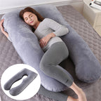 Woman lying on a large U-shaped gray body pillow on a bed.