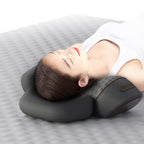 Person using a gray travel pillow on a bed