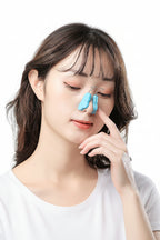 Woman with a blue strip on her nose against a gray background