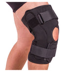 Black knee brace on a person's knee with a white background